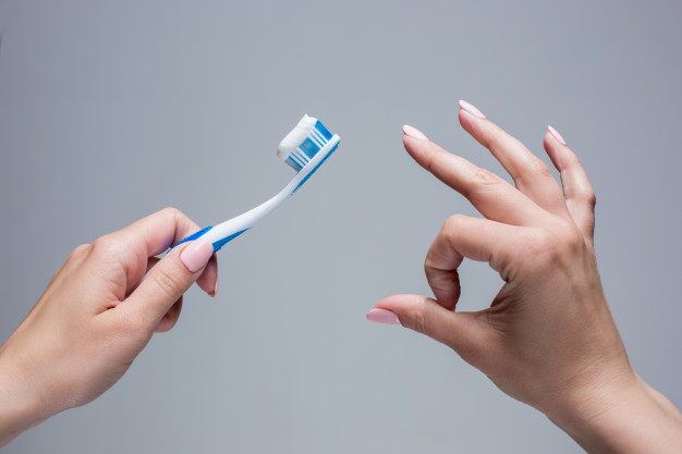 manos sujetando un cepillo de dientes.